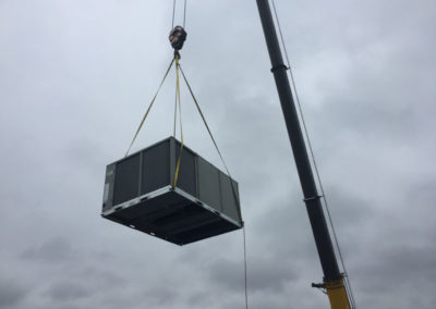 large commercial hvac unit lifted in the air by crane